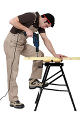 Carpenter drill through plank of wood