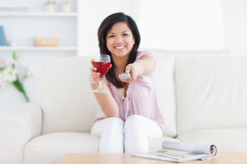 Obraz na płótnie Canvas Woman sitting in a white couch while holding a glass of red wine