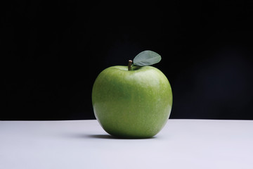 A green apple on a desk on black background
