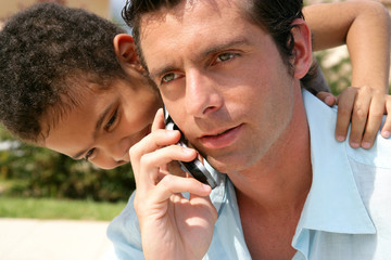 boy embracing his father while he is talking on his cell