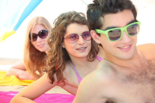 Three young men wearing sunglasses on the beach