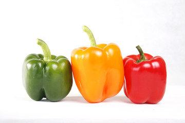 Three color red green yellow peppers in white background