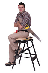 Laborer with saw sitting on a workbench