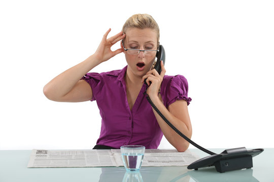 Woman reading a newspaper whilst on the phone