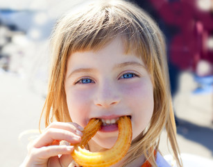 Naklejka premium Blue eyes little girl eating churros smiling