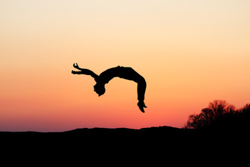 silhouette of gymnast doing a backflip in sunset - 41461736