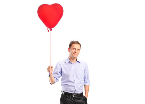 A Smiling Young Male Holding A Red Heart Shaped Balloon