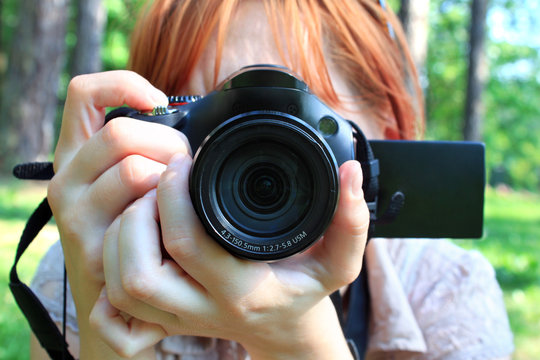 Girl holding a camera while taking outdoors pictures