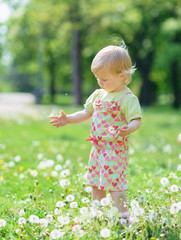 Baby playing with dandelions in park