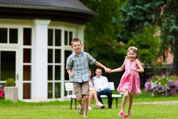 Family sitting and playing in front of their home