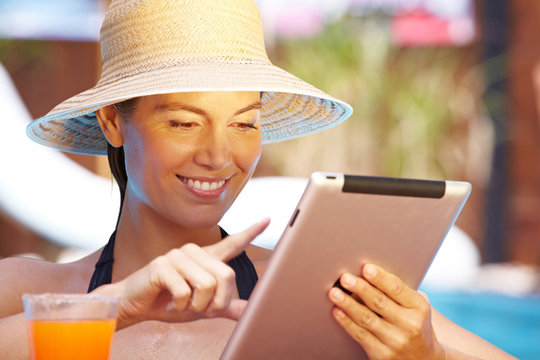 Frau mit Tablet-Computer am Pool