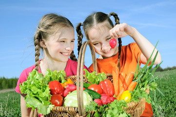 Two little girls with basket of vegetables