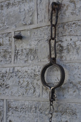 shackles and a chain hanging on the stone wall