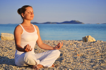 Fototapeta na wymiar Young woman during yoga meditation on the beach