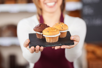 verkäuferin zeigt muffins in der bäckerei