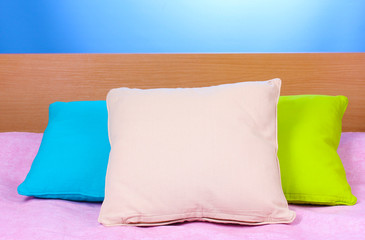 bright pillows on bed on blue background