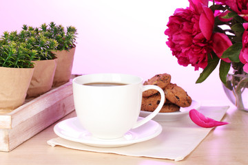 Fototapeta na wymiar filiżankę kawy, ciastka i kwiaty na stole w kawiarni