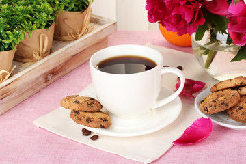 cup of coffee, cookies, orange and flowers on table in cafe
