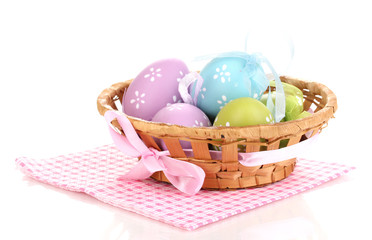 Colorful easter eggs in basket on napkin isolated on white