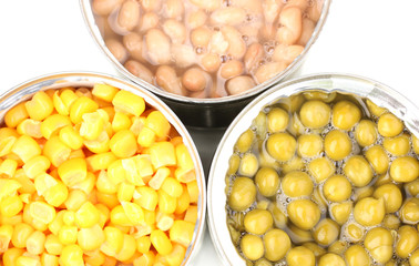 Open tin cans of corn, beans and peas close-up isolated on