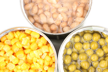 Open tin cans of corn, beans and peas close-up isolated on