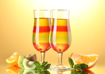 fruit jelly in glasses and fruits on yellow background