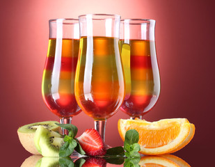 fruit jelly in glasses and fruits on red background