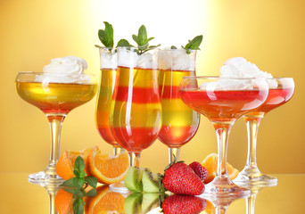 fruit jelly in glasses and fruits on yellow background