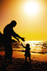 father and daughter playing on the beach at sunset