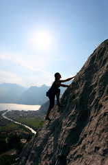 Silhouette of female climber against view of Lake Garda, Italy
