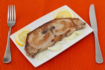 fried tuna with lemon and onion on the plate