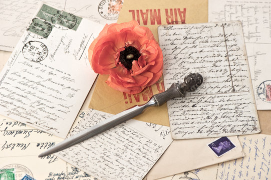 old post cards, stamps, letter opener and flower