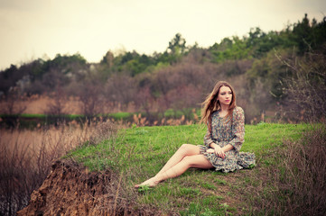 Naklejka na ściany i meble Beautiful young woman sitting on the grass