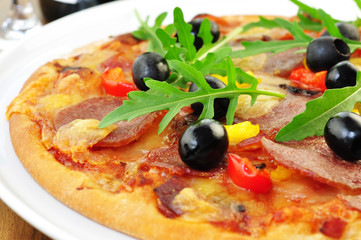 Pizza mit schwarzen Oliven und Rucola
