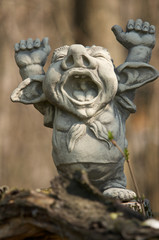 clay figure with hands up standing on a trunk