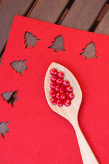 Wooden spoon with red candies in red background