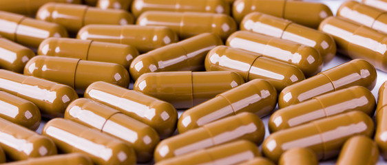 Brown capsule pills close-up, background