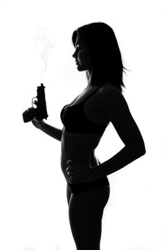 Silhouette of beautiful bondgirl with smoking gun