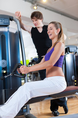 Sport - Paar trainiert an Kraftmaschinen im Fitnessstudio