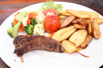 Grilled steak with vegetables on wood background