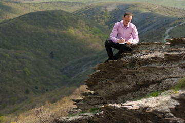 man with notepad on stone