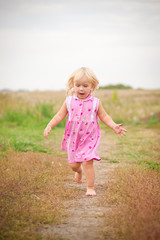 Adorable baby running by road in field