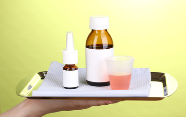 Hand holding tray with medicines on green background