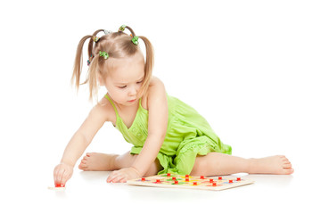 little girl in green dress playing puzzle game on floor on white