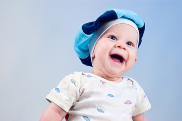 Amusing baby boy in a beret in a studio on a dark blue backgroun