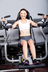 Fototapeta na wymiar fitness woman exercising with peck deck machine in gym