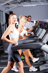 Fototapeta na wymiar group of fitness people running on treadmill in gym