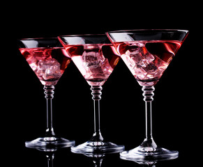 Red cocktail in martini glasses isolated on black