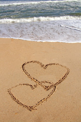 handwritten heart on sand with wave approaching
