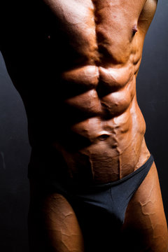 closeup of bodybuilder abdomen on black background